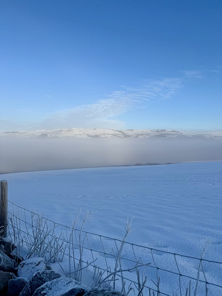 A photo taken from above the layer of cloud shrouding the valley beneath.