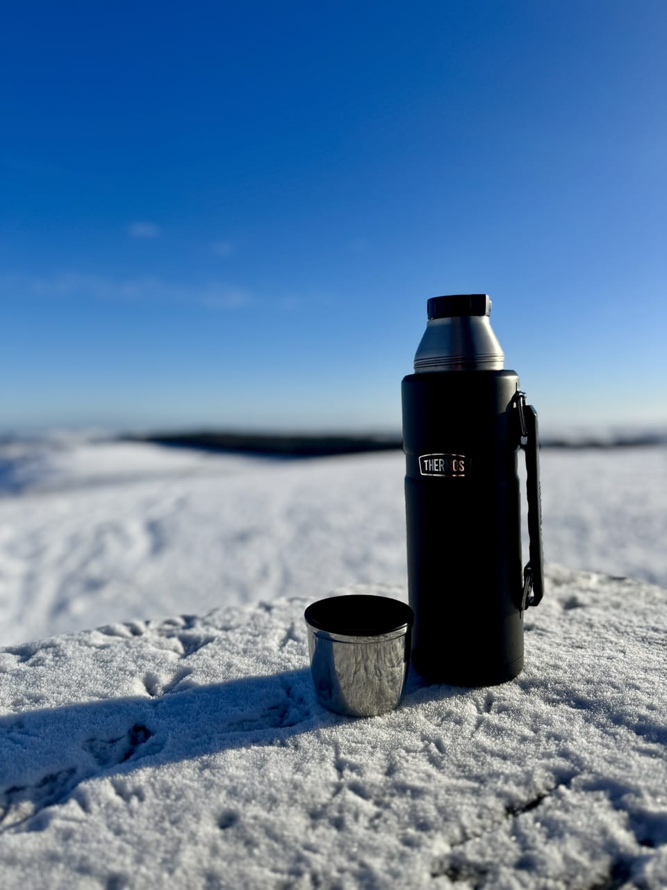 A Thermos flask sits on a snow-topped ledge surrounding the balcony of the monument.