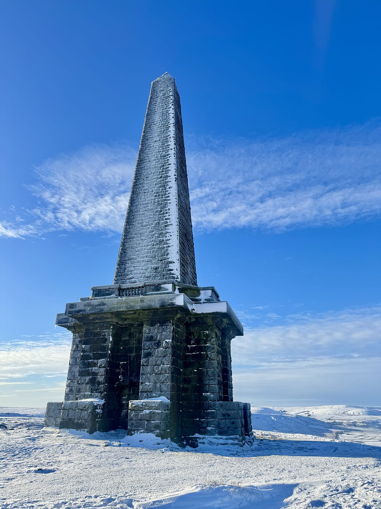 A close photo of an icy Stoodley Pike monument towering above me.